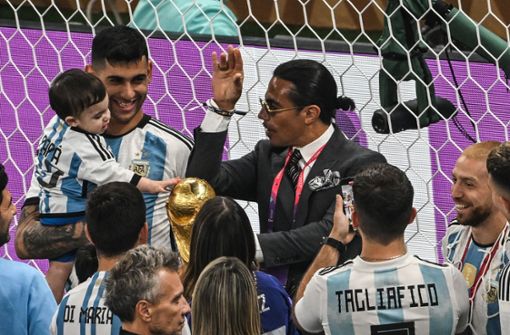 Salt Bae (Mitte) versucht bei der WM-Feier vergeblich, die Aufmerksamkeit von Lionel Messi zu gewinnen. Foto: dpa/Robert Michael