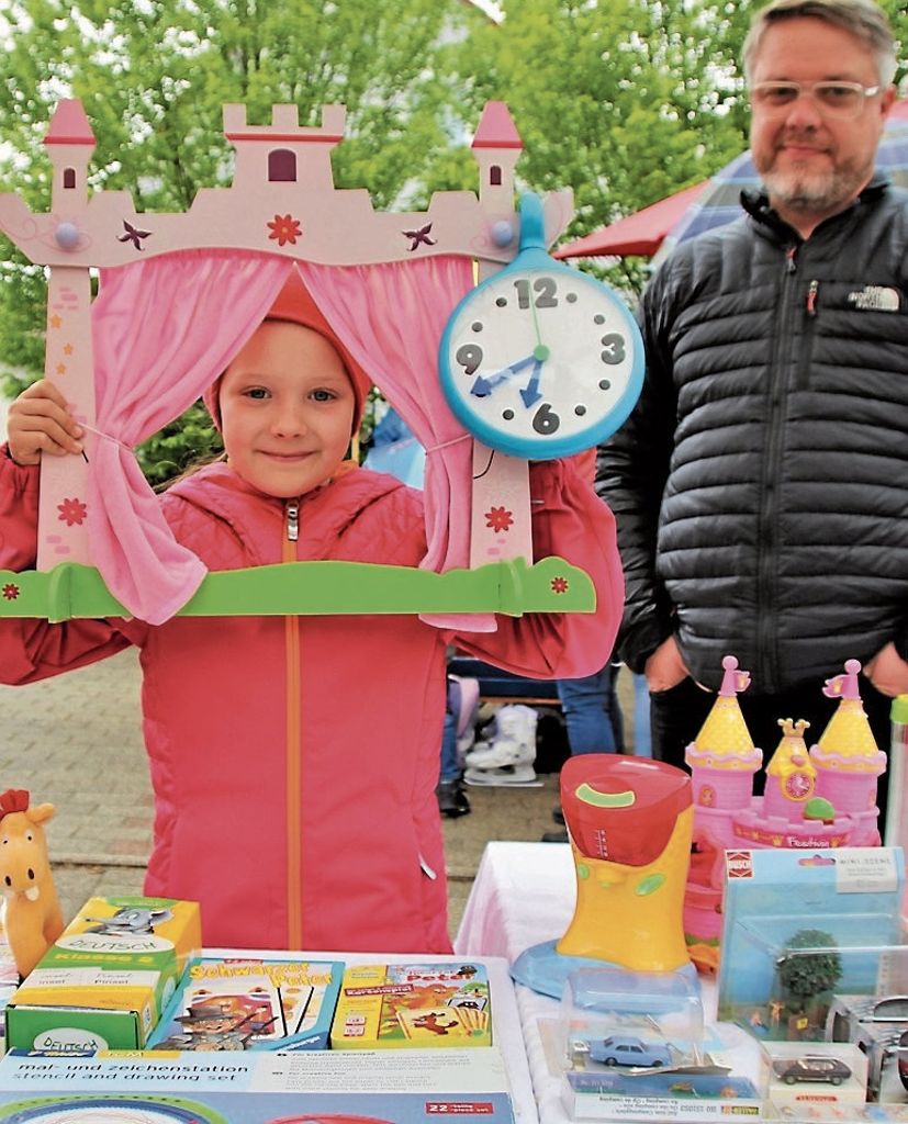 Die achtjährige Loki hat für den Kinderflohmarkt einige Spielsachen aussortiert. Der Papa hilft beim Verkauf.
