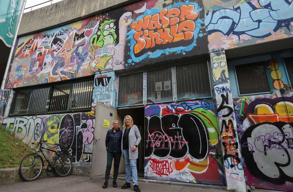 „Wasenschule“ steht in Orange als Graffiti über der Eingangstür. Davor:  Tamara Marshall (links), Bildungsbeauftragte des Schaustellerverbands Südwest Stuttgart und Bereichslehrerin Sabine Biebries.