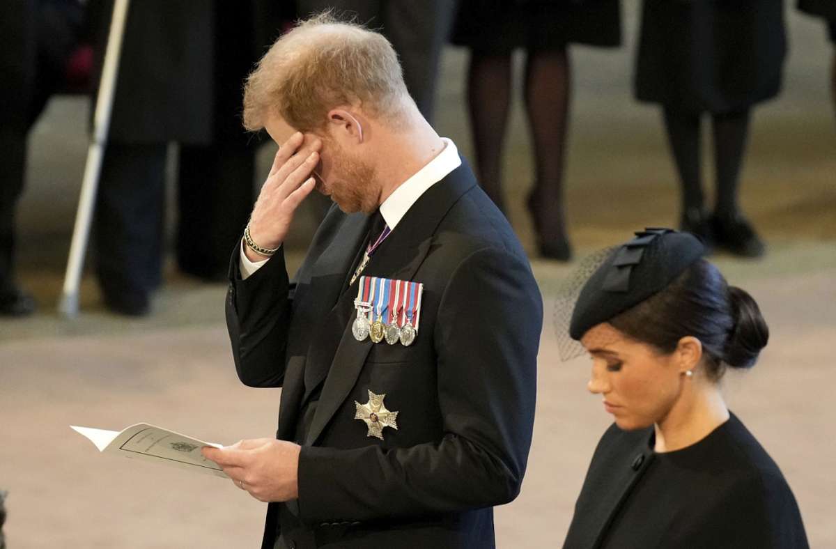 Prinz Harry wischt sich eine Träne aus dem Augenwinkel. Neben ihm: Seine Frau Herzogin Meghan.