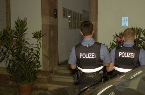 Polizeibeamte stehen vor dem Hauseingang der tatverdächtigen Frau. Foto: dpa/Thorsten Kremers