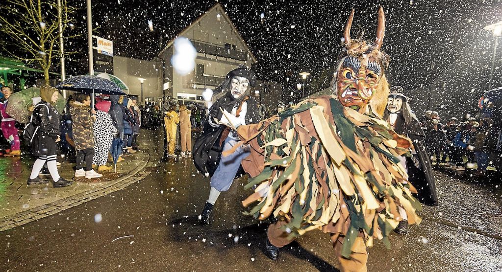 WOLFSCHLUGEN: Hexen, Clowns und Guggenmusiker unterhalten die Besucher bestens beim Nachtumzug: Schnee trübt die Sicht, aber nicht die Stimmung