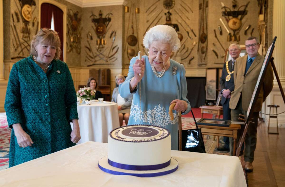 Die Queen schneidet die Torte an, die zu ihrem Platin-Jubiläums während eines Empfangs im Ballsaal von Sandringham House bereit steht Foto: dpa/Joe Giddens