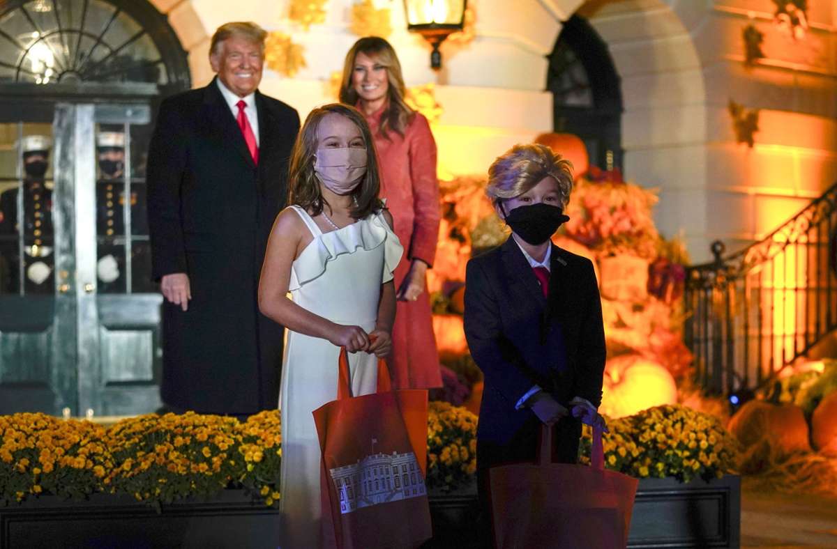 Donald und Melania Trump posieren für ein Foto mit zwei Kindern, die sich als der Präsident und die First Lady verkleidet haben.