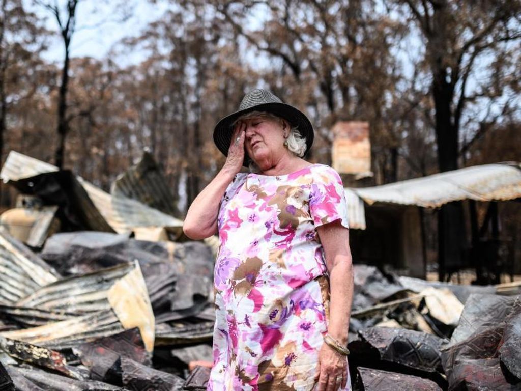Eine Frau steht im Ort Mogo vor den Überresten ihres Geschäfts, das an Silvester abgebrannt ist. Foto: James Gourley/AAP/dpa
