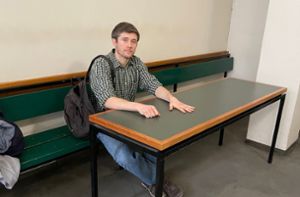 Klimaaktivist Henning Jeschke sitzt festgeklebt an einem Tisch in einem Raum des Amtsgericht Tiergarten. Foto: dpa/Anne Baum