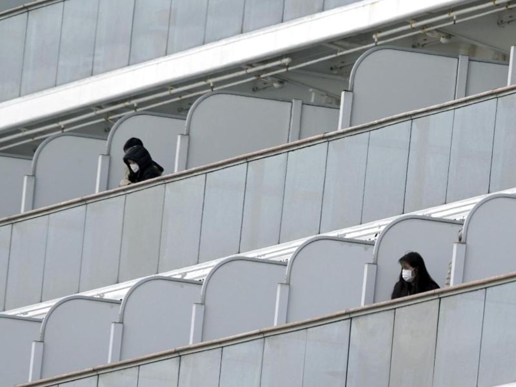 Passagiere mit Mundschutz auf Balkonen des Kreuzfahrtschiffs «Diamond Princess» im Hafen von Yokohama. Foto: Eugene Hoshiko/AP/dpa
