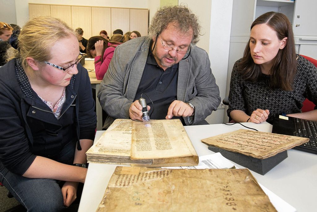 Sarah Kupferschmied, Mark Mersiowsky und Patrizia Hartich (von links) schauen sich die mittelalterlichen Handschriften genau an.