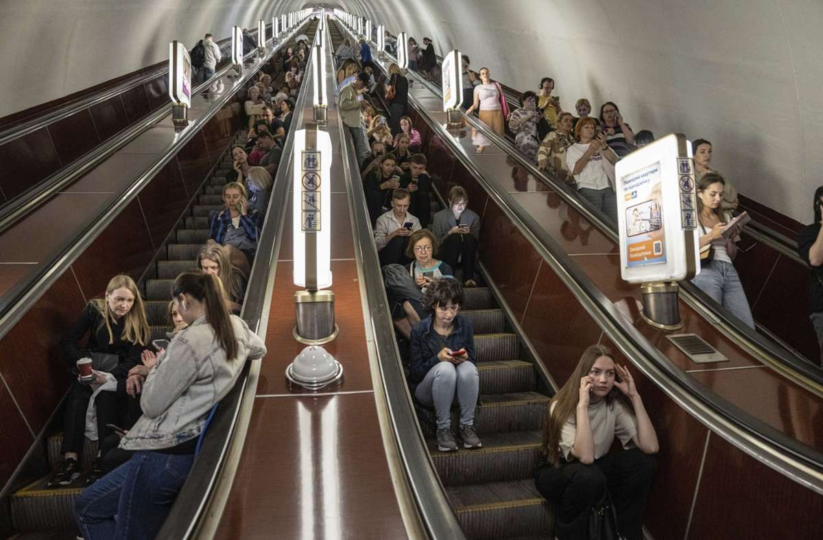 Menschen sitzen auf einer Rolltreppe, während sie in einer Metrostation der ukrainischen Hauptstadt Kiew Schutz vor russischen Raketen- und Drohnenangriffen suchen.