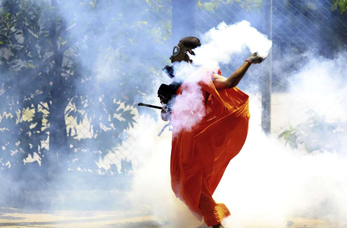 Ein Mann wirft eine Tränengasgranate zurück, die von der Polizei abgefeuert wurde, um Demonstranten zu vertreiben, die den Rücktritt von Präsident Rajapaksa forderten. Foto: dpa/Amitha Thennakoon