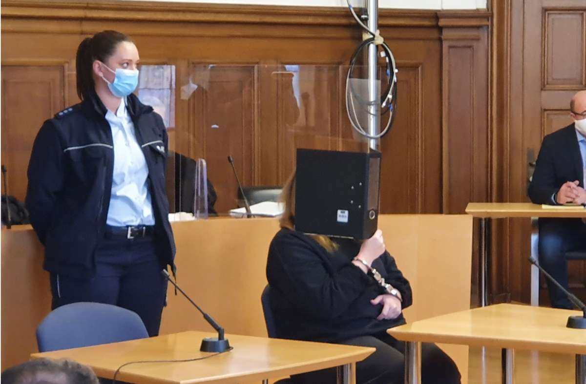 Die Angeklagte hält sich vor Prozessbeginn einen Aktenordner vor das Gesicht. Darunter trägt sie eine Maske, die sie den ganzen Prozesstag über nicht abzieht. Foto: /Wein