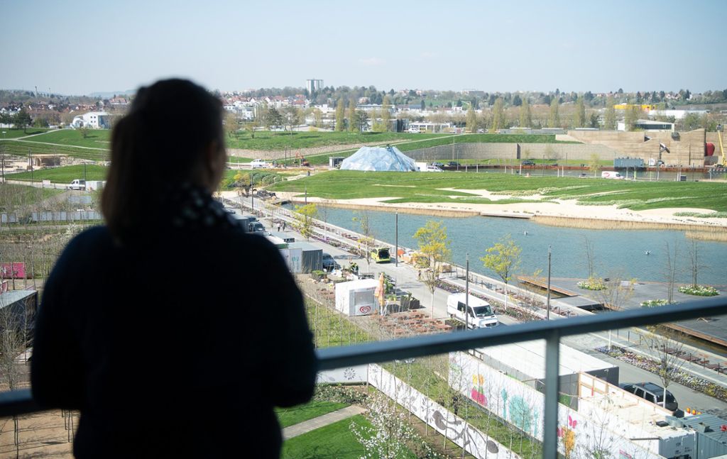 Eine Frau schaut von einem Balkon eines Wohngebäudes der Stadtausstellung auf das Gelände der Bundesgartenschau. Die Bundesgartenschau wird am 17. April eröffnet.