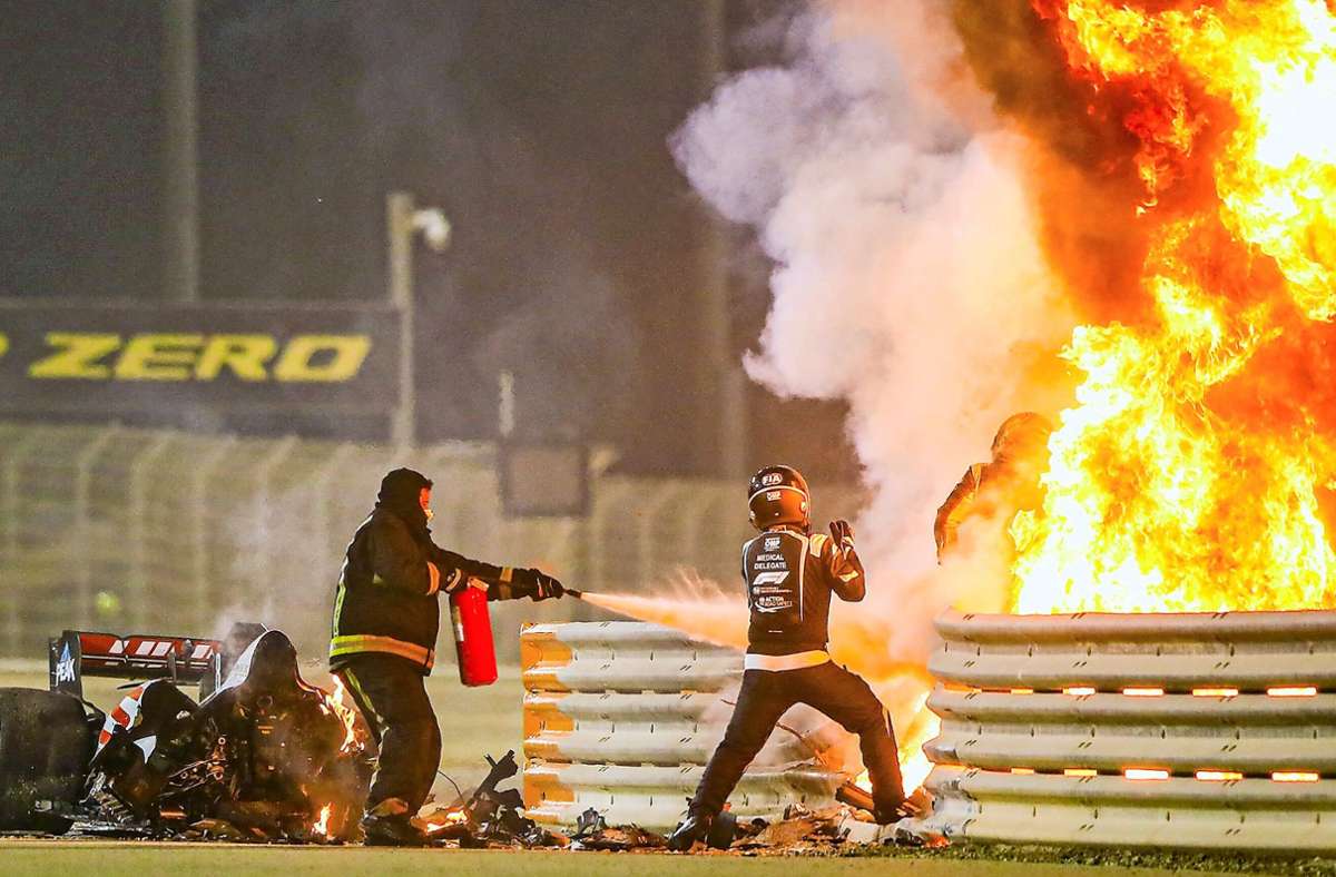 Romain Grosjean (re.) entkommt der Flammenhölle – die Rettungskräfte unterstützen ihn.