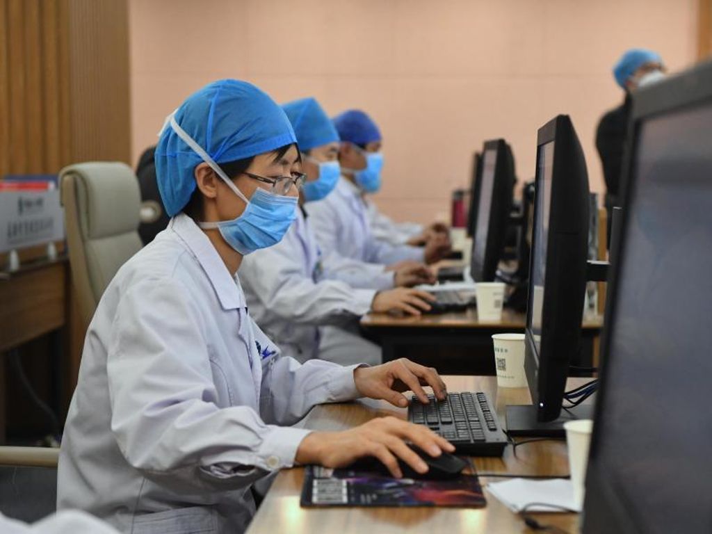 Medizinische Spezialisten mit Mundschutz und Kopfhauben sitzen vor Computern, und bieten Online-Dienste für Patienten im Henan Provincial Peoples Hospital in der Provinz Henan in Zentralchina an. Foto: Li Jianan/XinHua/dpa