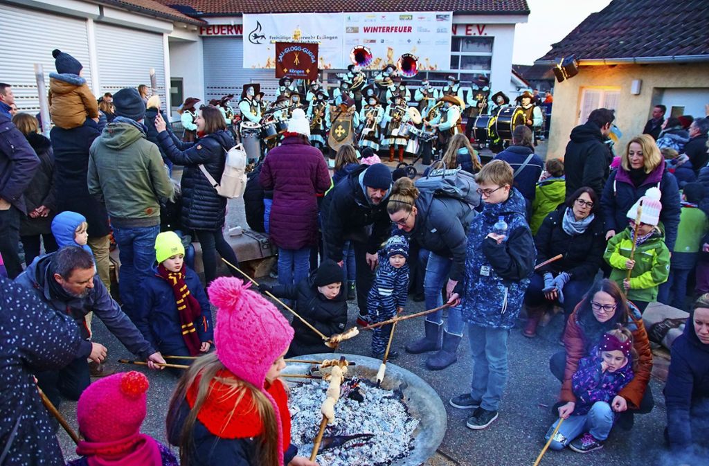 Kinder und Eltern backen am offenen Feuer ihr Stockbrot. Viele Besucher lassen sich derweil von der Guggenmusik-Kapelle unterhalten.