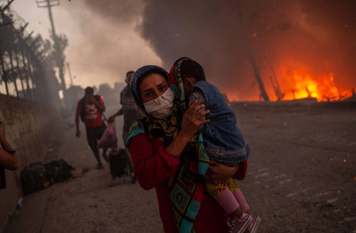 Ihre Kinder auf dem Arm versuchen die Flüchtlinge von Moria, den Flammen zu entkommen.