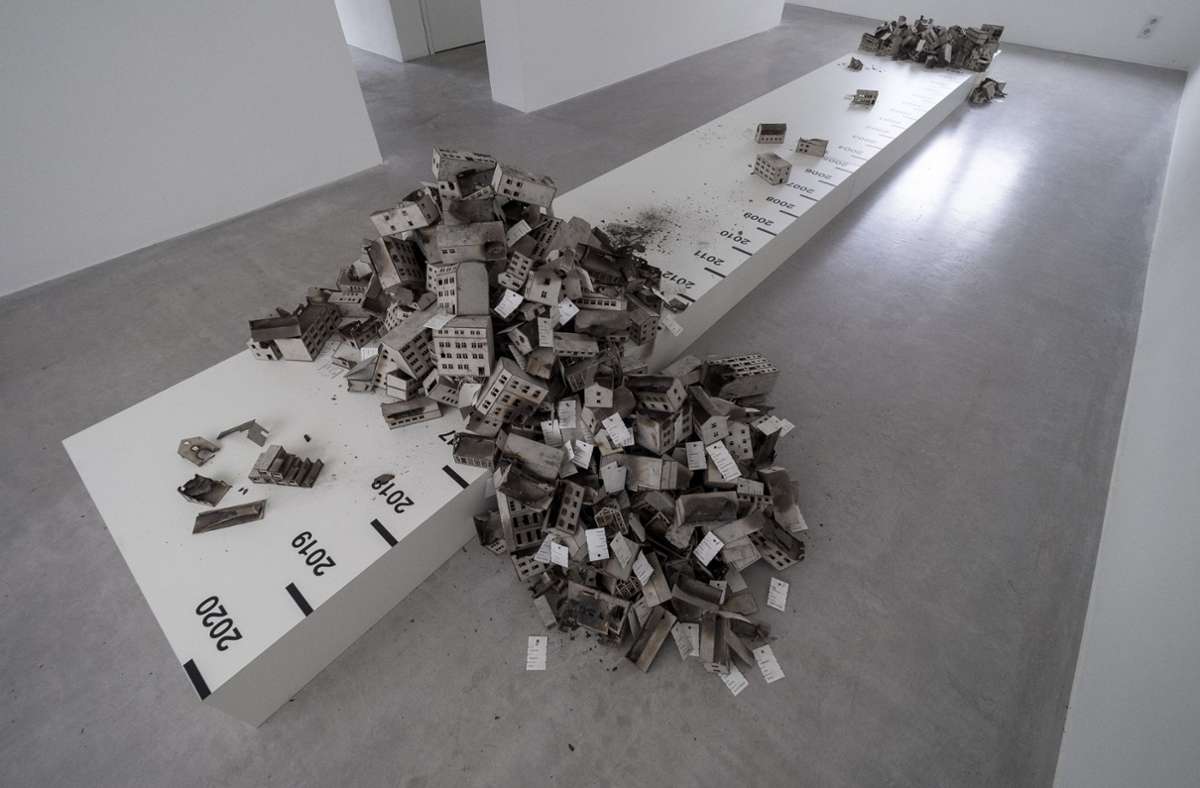 Der Informationsdesigner Thomas Stratmann hat in der Architekturgalerie am Weißenhof am Boden für seine Installation „Das Brandstiftungsarchiv / The Arson Archive“ ein flaches Podest installiert, das mit einer Zeitleiste versehen ist.