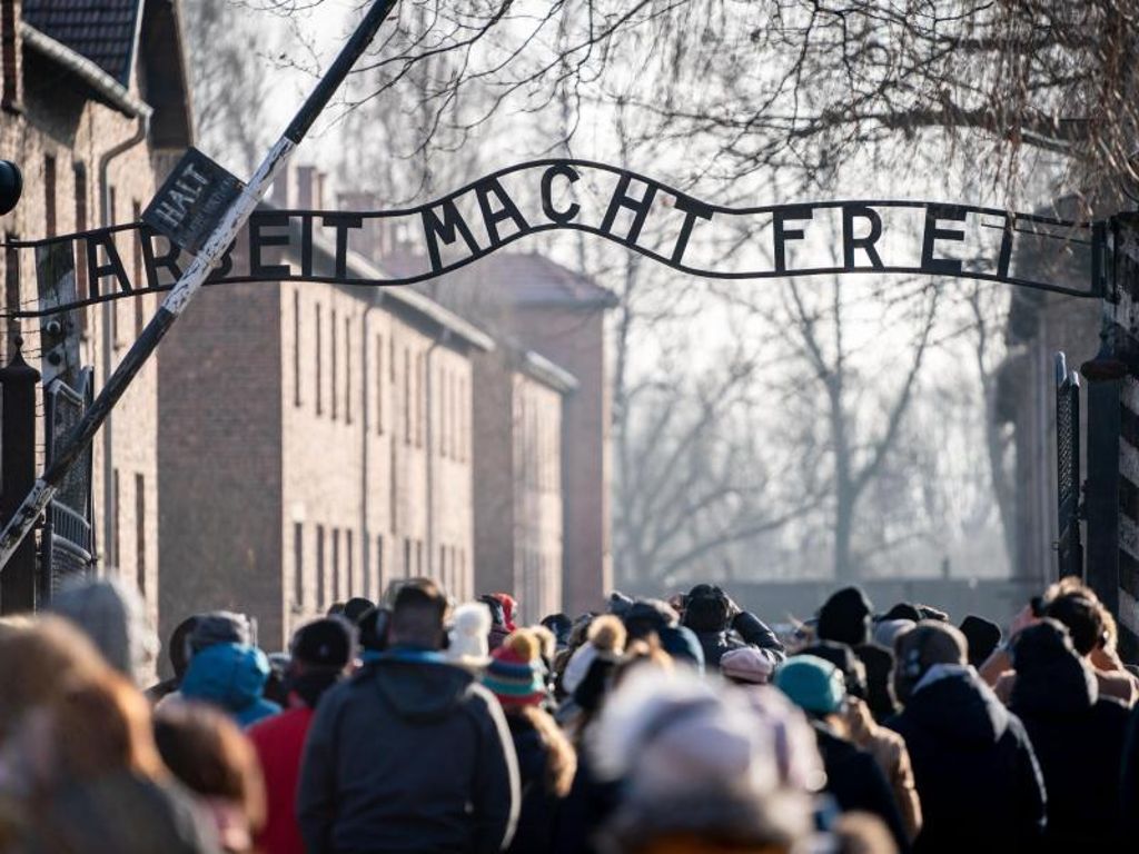 Besucher gehen durch den Eingang mit dem Schriftzug «Arbeit macht frei» in das frühere Konzentrationslager Auschwitz in Oswiecim. Foto: Kay Nietfeld/dpa