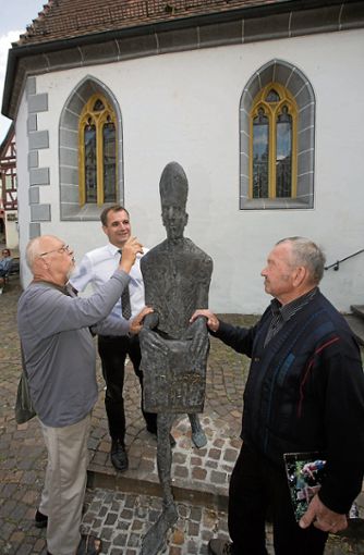 Bildhauer Karl Ulrich Nuss erläutert Bürgermeister Frank Buß und Philipp Bender (von links), dem Stifter der Skulptur, sein Kunstwerk, das vor der Ottilienkapelle steht. Foto: Bulgrin Quelle: Unbekannt